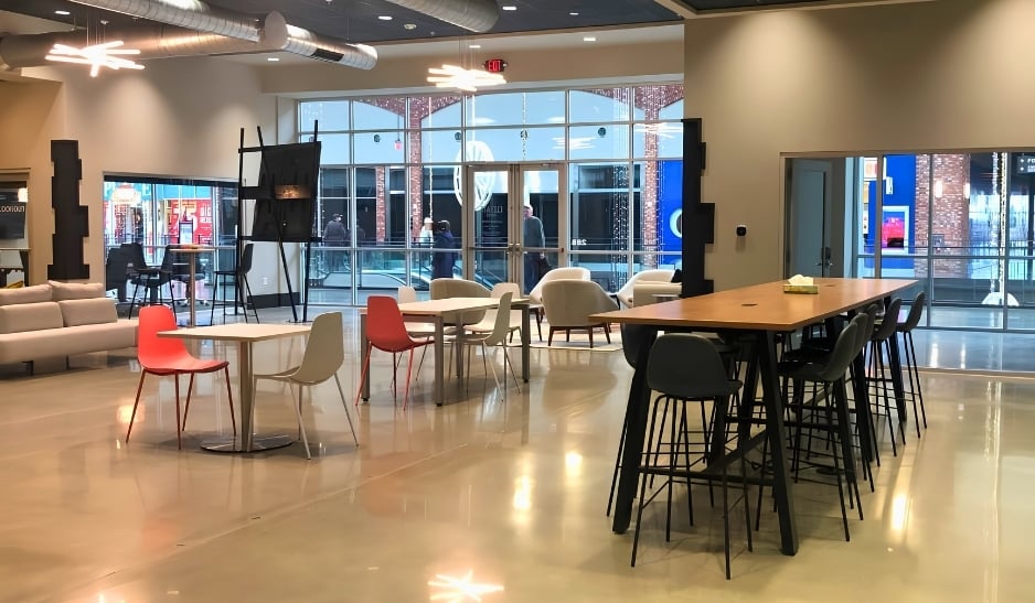 Open lounge and co-working area with high-top tables, lounge chairs, and large windows.